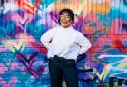 A smiling woman stands in front of colorful graffiti representing the inclusive environment at NeuroSpark Health.