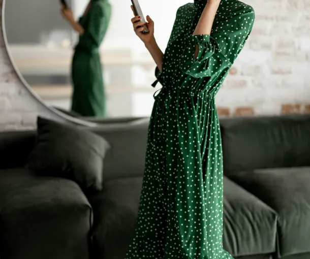 Woman in a green dress, wearing headphones and holding a cell phone, representing ADHD criteria from the DSM-5-TR.
