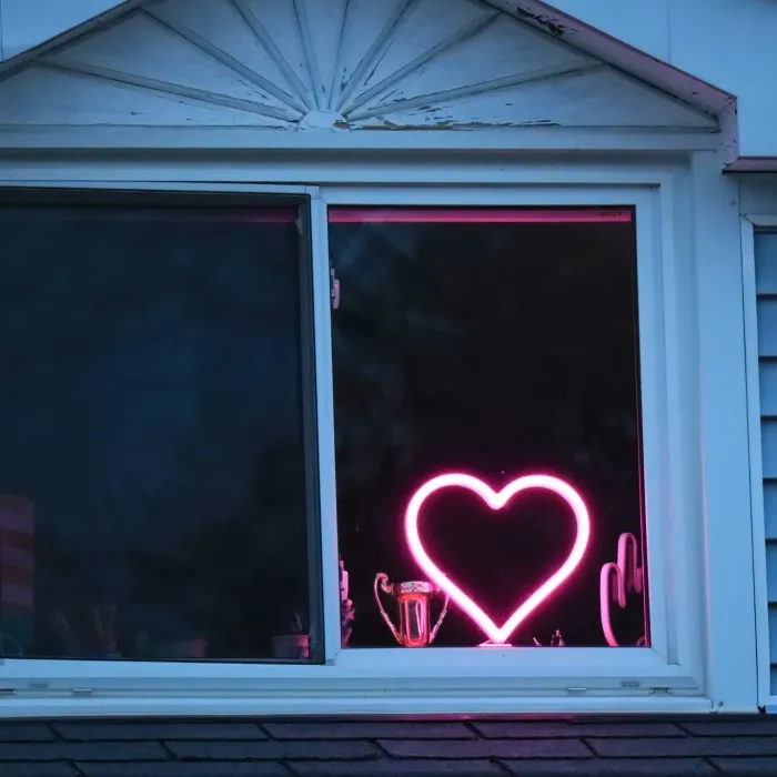 Pink neon heart shaped sign in the window of a house representing the social aspects of the SRS and autism assessment process.