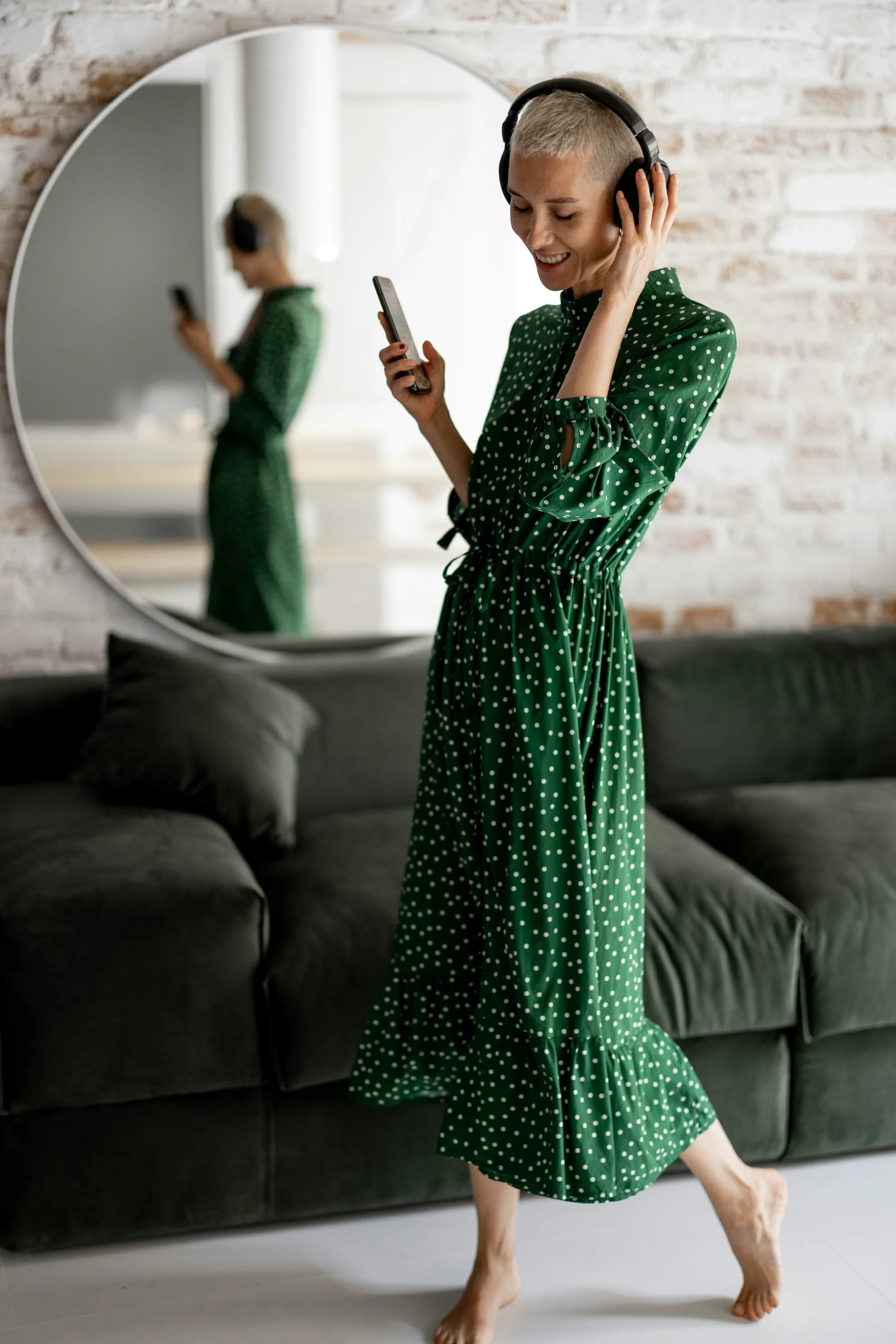 Woman in a green dress, wearing headphones and holding a cell phone, talking with NeuroSpark about the ADHD diagnostic criteria.
