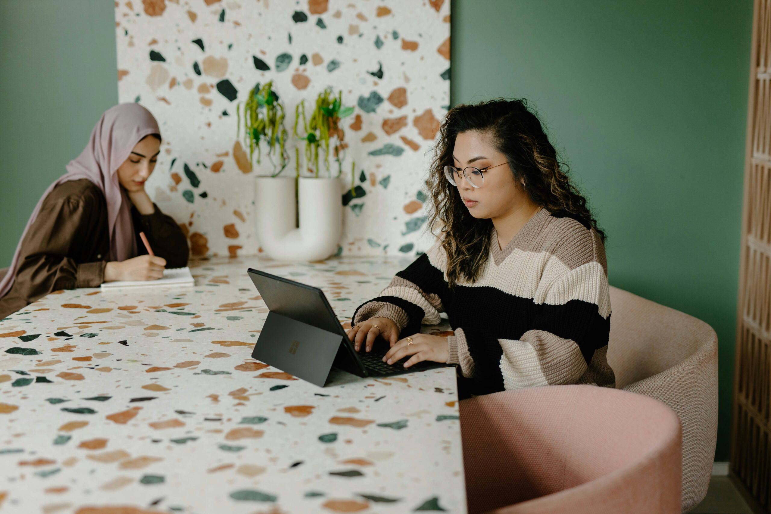 Two women sitting at a colorful table.