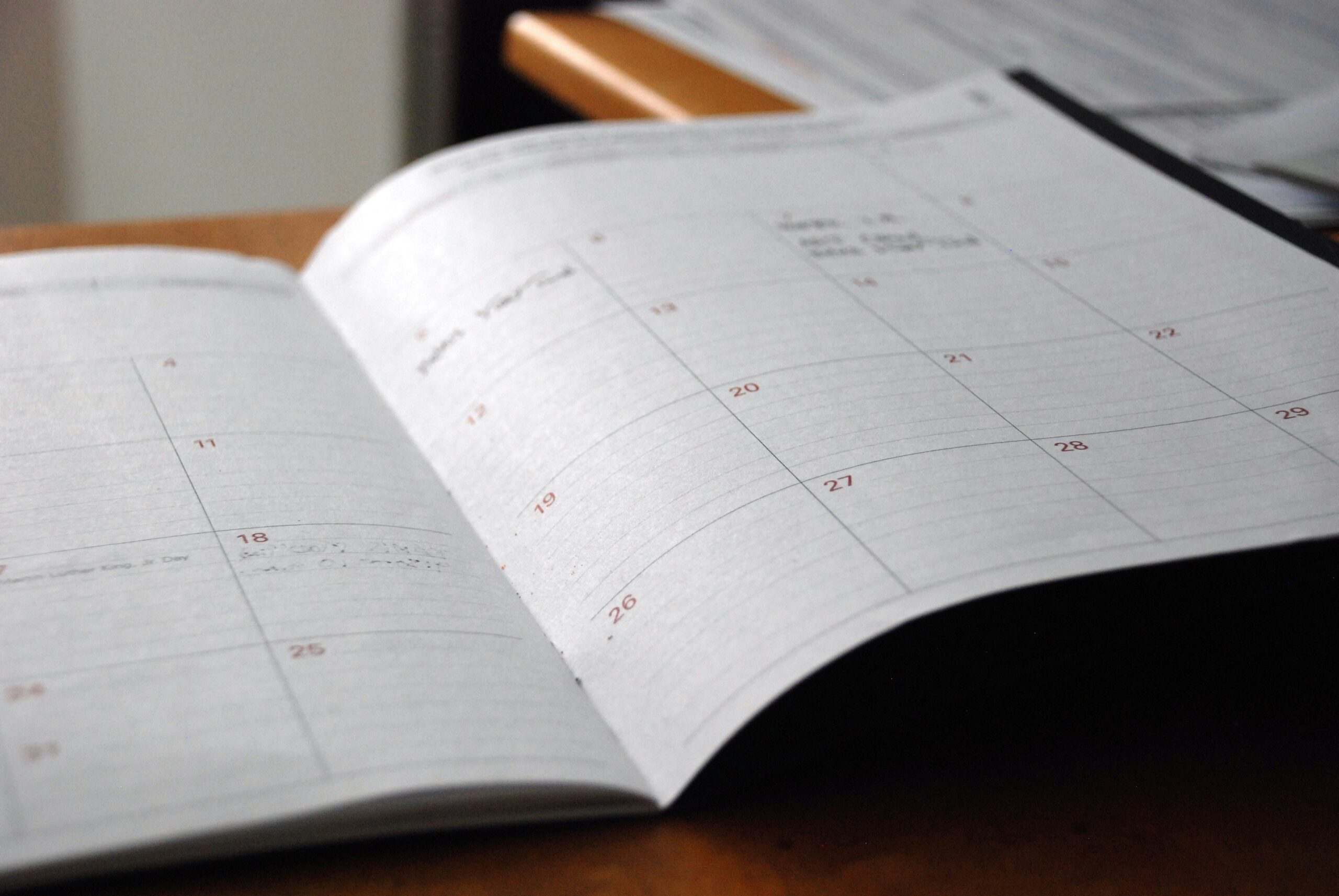 A paper calendar sits on top of a desk, representing the scheduling process of neurodiversity-affirming therapy.
