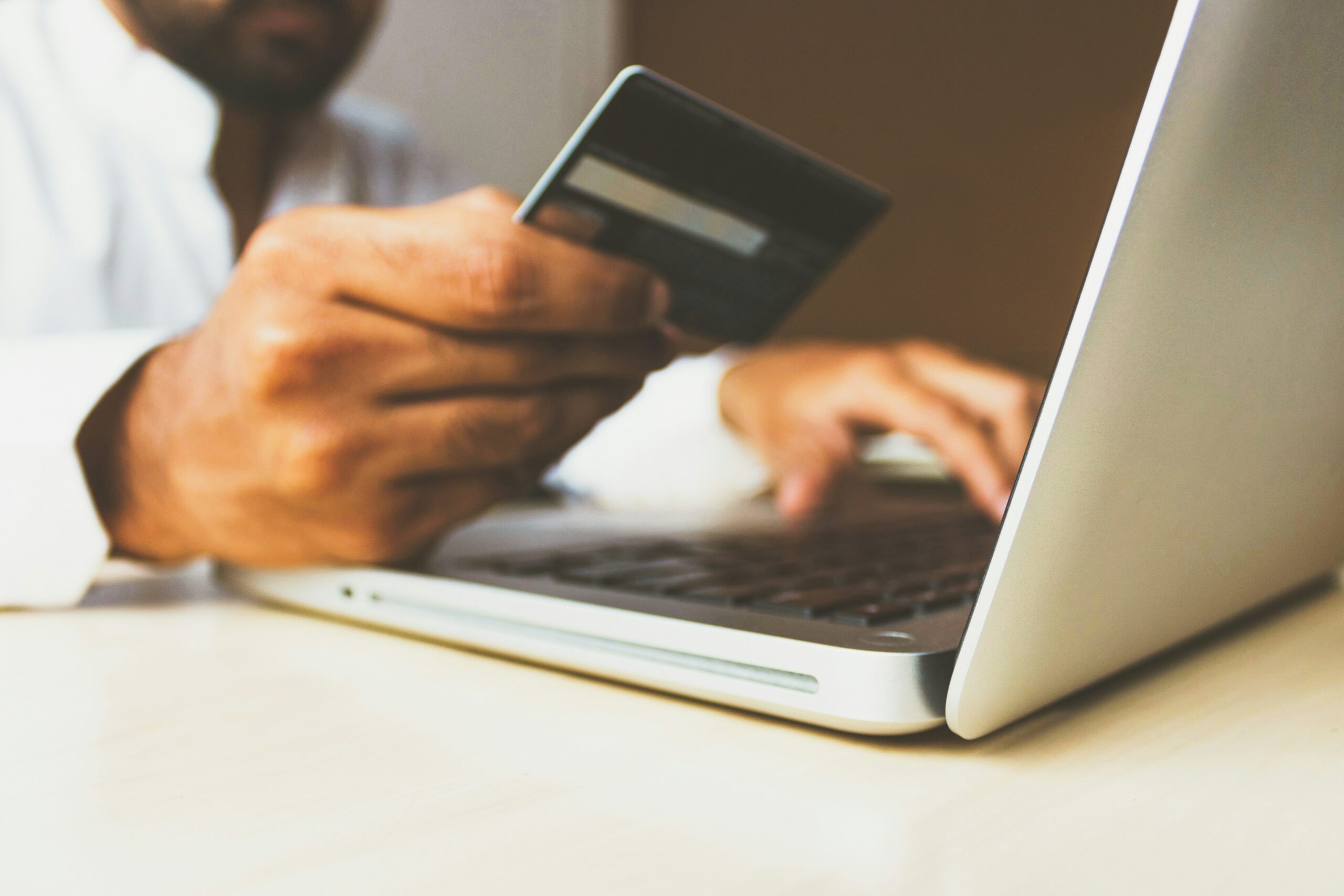 A person works at a laptop with a credit card in hand, used to pay for neurodiversity-affirming therapy.