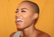 A woman in front of an orange background smiles after finding NeuroSpark Health.