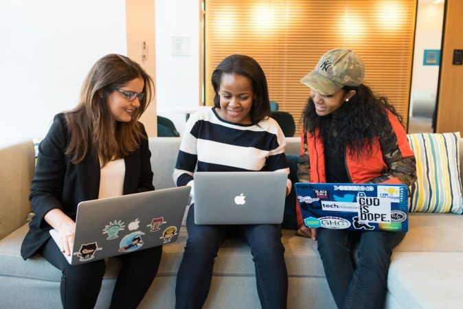 Three friends work on their laptops together applying for NeuroSpark Health careers.