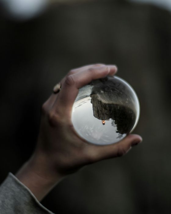 A hand holds up a crystal ball symbolizing the clarity gained from an adult AuDHD assessment.