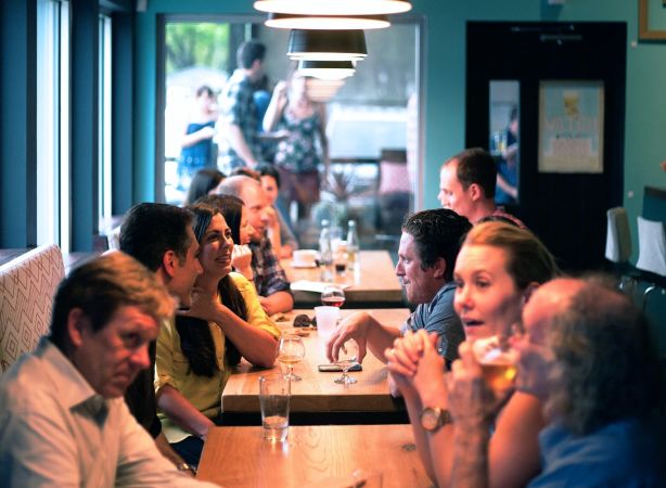 A group of friends sit together at a table while discussing NeuroSpark Health careers.