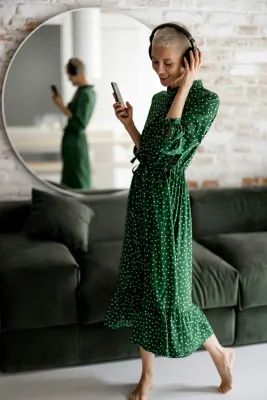 Woman in a green dress, wearing headphones and holding a cell phone, talking with NeuroSpark about the ADHD diagnostic criteria.