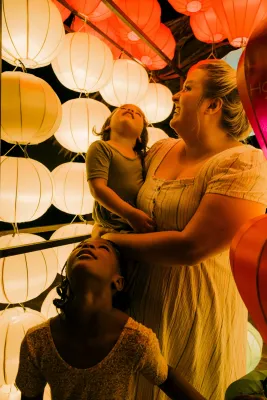 Woman with two kids looking at a sensory light exhibit and considering autism assessment using the MIGDAS-2.