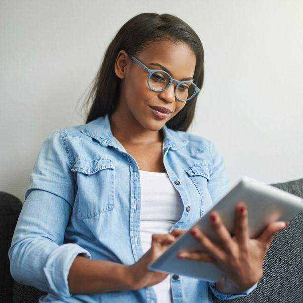 Woman sitting on a couch using an iPad while researching autism vs ADHD assessment options