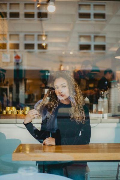 A woman in a cafe looks through a window representing autistic assessment client in California.