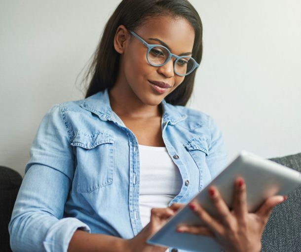 Woman sitting on a couch using an iPad while researching autism vs ADHD assessment options