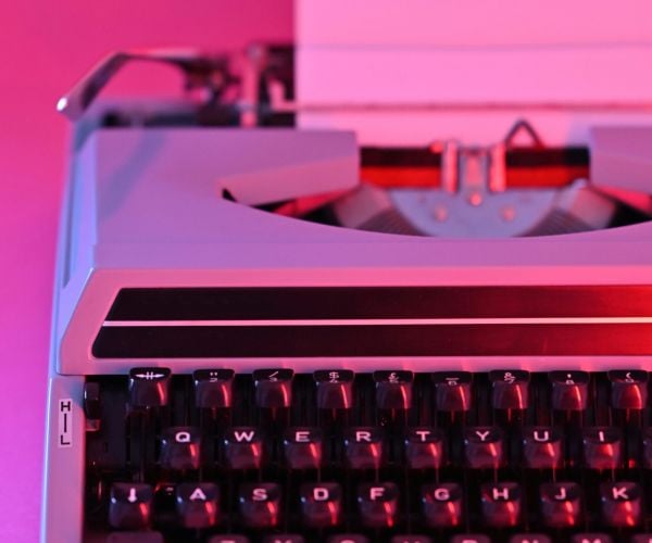 Hot pink typewriter and background represent NeuroSpark Health's Dear AuDHD Auntie advice column.