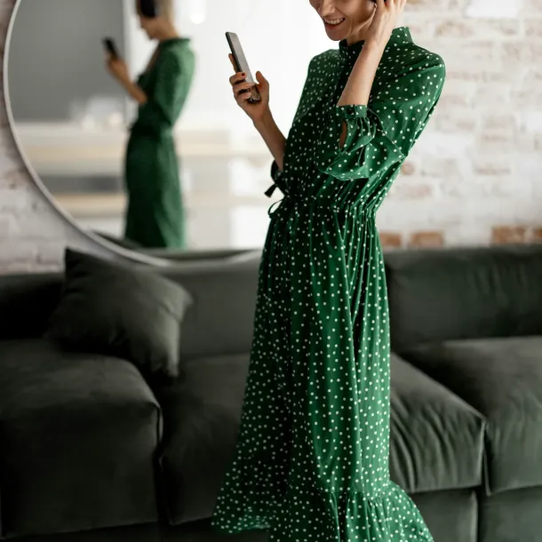 Woman in a green dress, wearing headphones and holding a cell phone, talking with NeuroSpark about the ADHD diagnostic criteria.