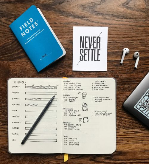 A notebook, field guide, and earpods sit on a desk before beginning the virtual support services offered for autistic adults at NeuroSpark Health.