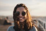 A happy woman wears sunglasses and smiles after her adult autism evaluation with NeuroSpark Health.