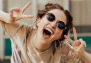 A woman wearing sunglasses holds up her hands in peace signs celebrating her recent adult autism diagnosis.
