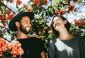 A couple stands under flowers smiling at each other celebrating an adult autism diagnosis.